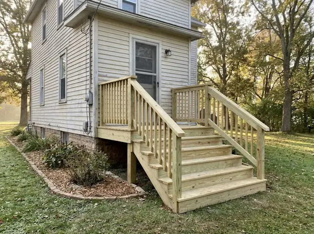 Freshly rebuilt wooden back steps with a handrail leading to a back door