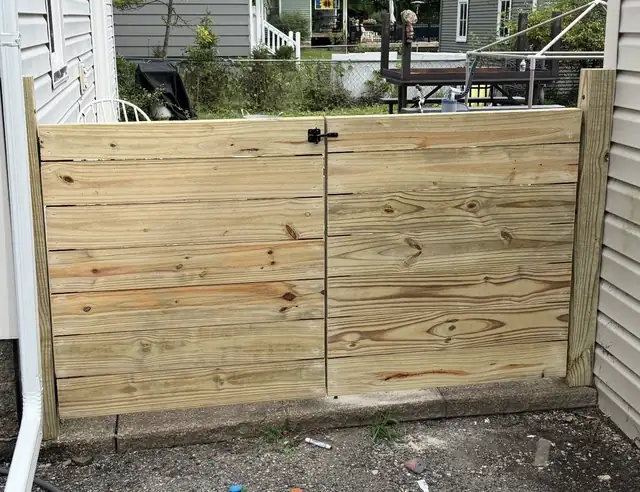 New double wood gate in a pressure-treated board fence